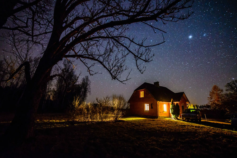 Hus i natten med stjärnor i himlen