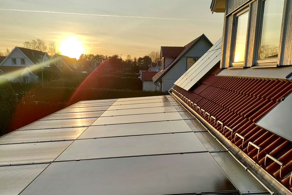 Solcellspaneler på ett villatak i solnedgång